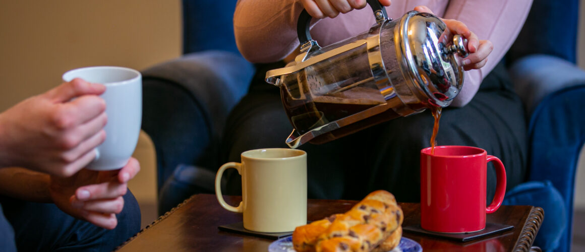 Two people drinking coffee at a table with pastry.