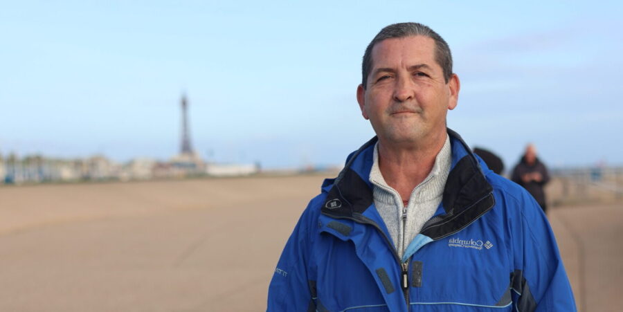 Ian - a man standing with a blue jacket on his own