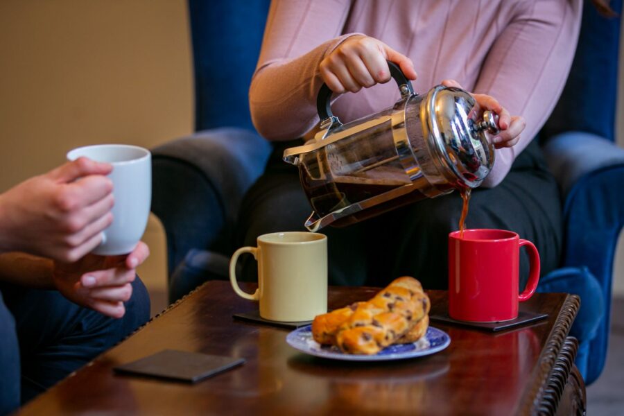 Two people drinking coffee at a table with pastry.